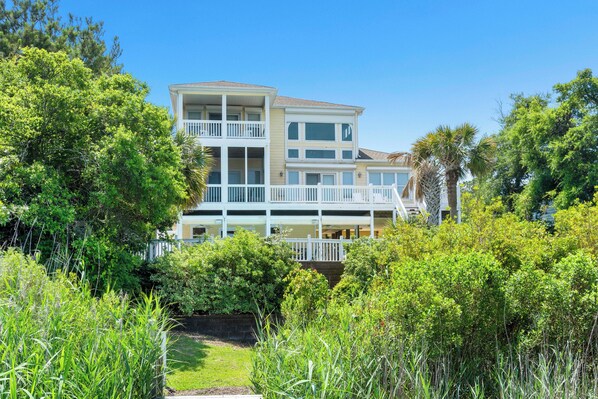 A multi-story building with balconies, surrounded by lush greenery and trees. - Soundfront | Pool + Game Room + Private Pier (Emerald Isle)
