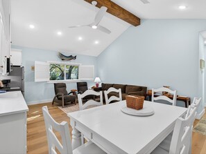 Un coin repas avec une table blanche, des chaises et un ventilateur de plafond.