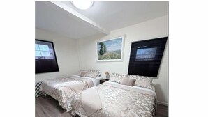 Ein Schlafzimmer mit zwei Betten, einem Oberlicht und einem Fenster mit Jalousien.