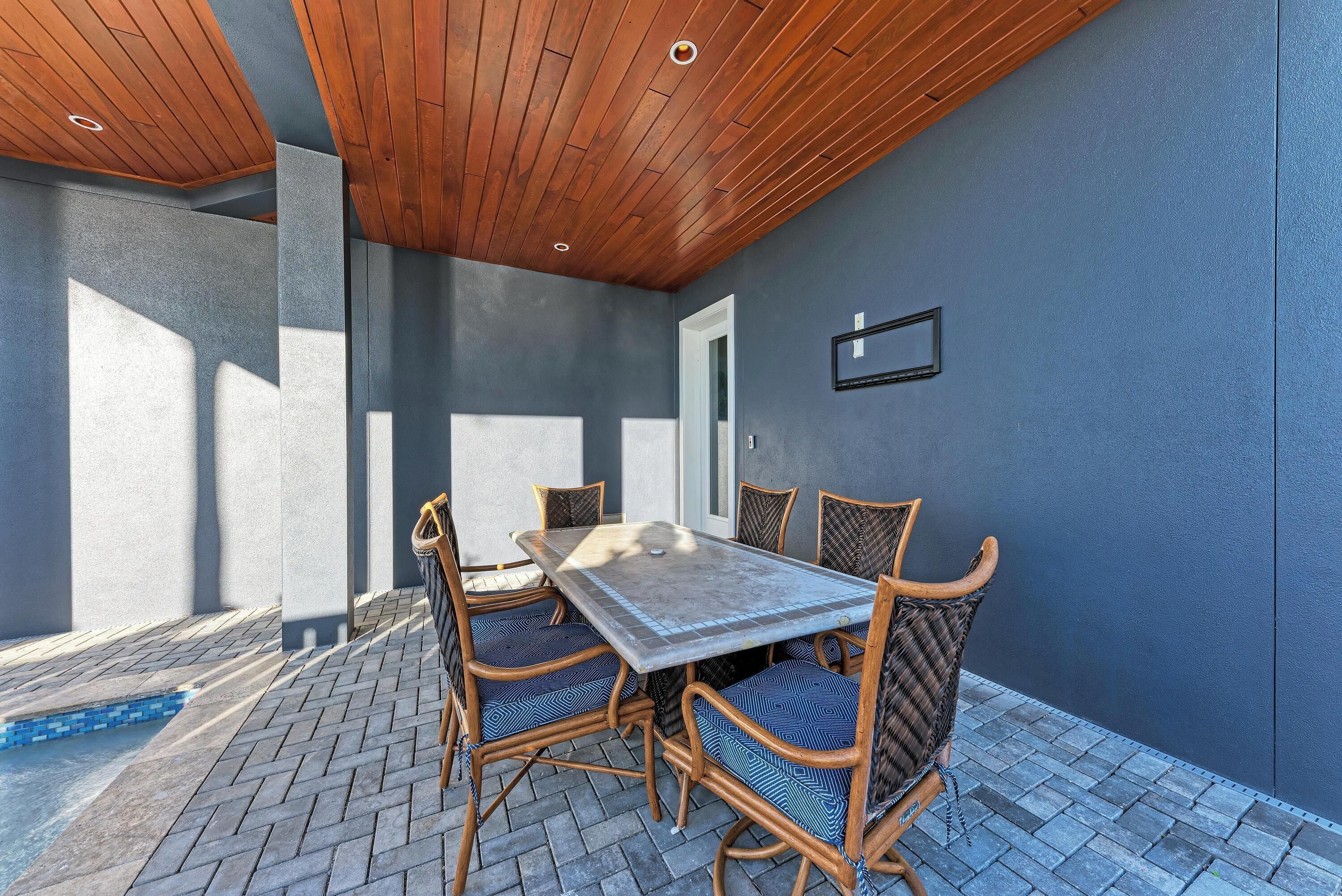 Un patio al aire libre con mesa y sillas, una piscina y techo de madera.