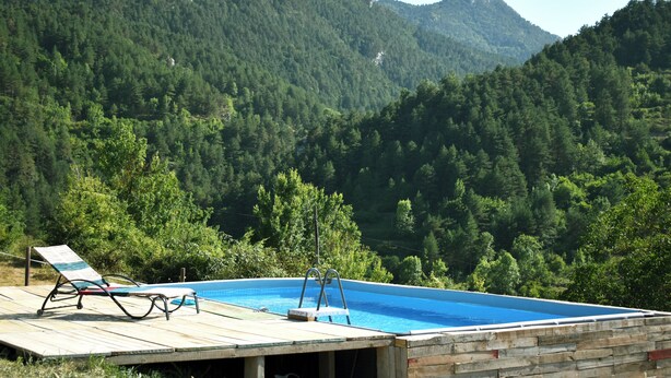 A wooden deck with a pool and lounge chairs overlooking a forested mountain. - Mountain, sports and wellness in Más El Prat (pet friendly) (La Pobla de Lillet)