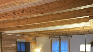A cozy room with a sofa, a flat-screen TV, a lamp, and a window with curtains. - Mountain, sports and wellness in Más El Prat (pet friendly) (La Pobla de Lillet)
