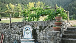 A stone wall with a tiled fountain, steps, and potted plants. - Mountain, sports and wellness in Más El Prat (pet friendly) (La Pobla de Lillet)