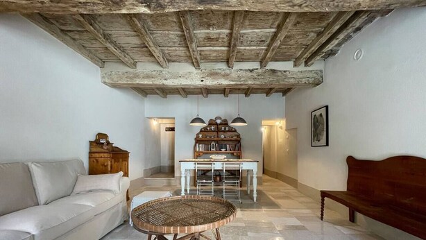 Una sala de estar con un sofá, una mesa de mimbre, un banco de madera y una mesa de comedor con sillas.