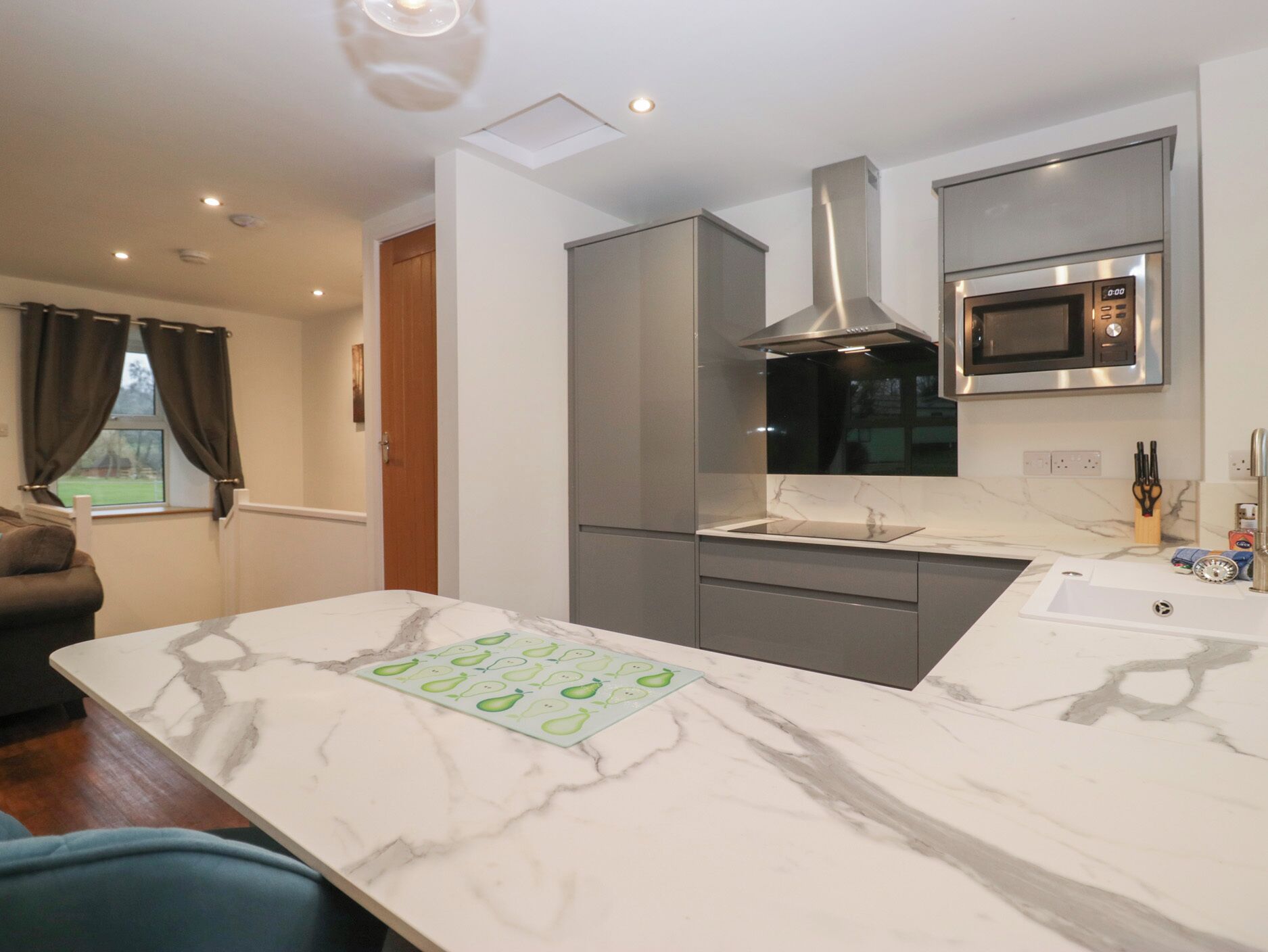 A modern kitchen with a marble countertop, stainless steel appliances, and a view of the outdoors.
