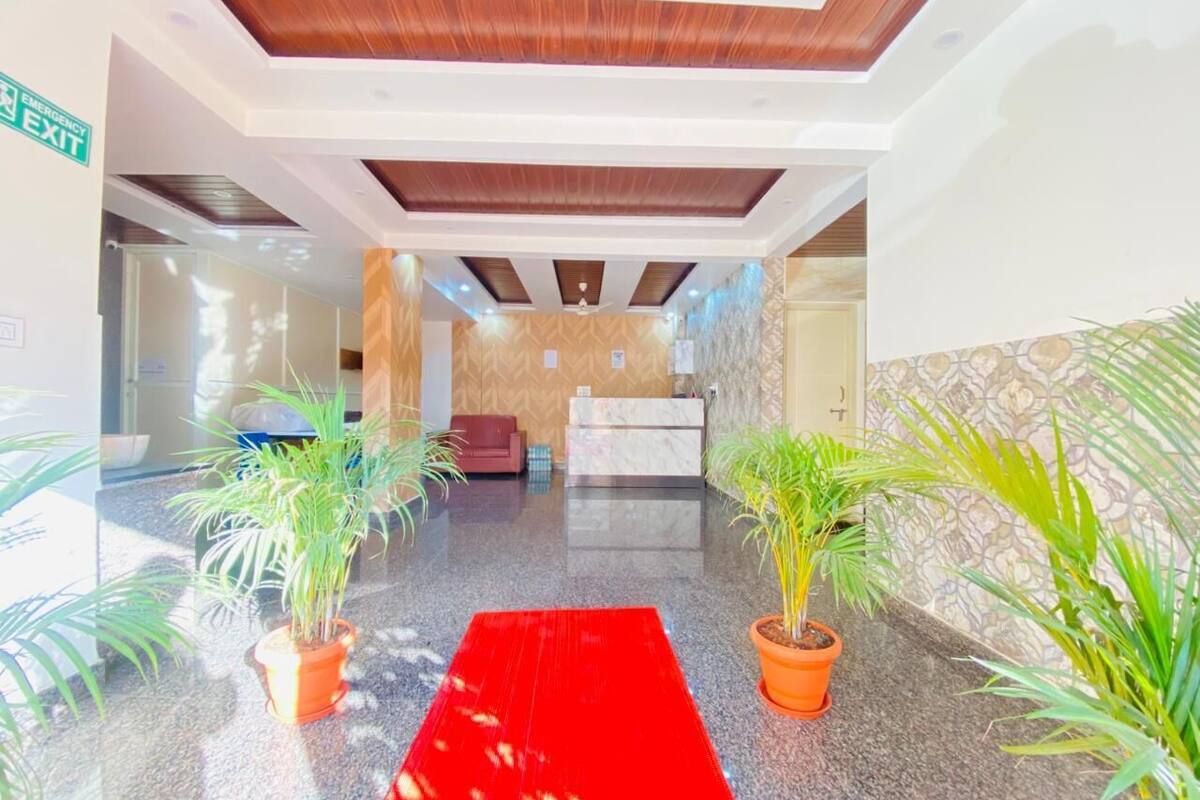 A hotel lobby with a red carpet, reception desk, and potted plants.