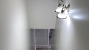 Una scala in legno con pareti bianche e un lampadario in cima.
