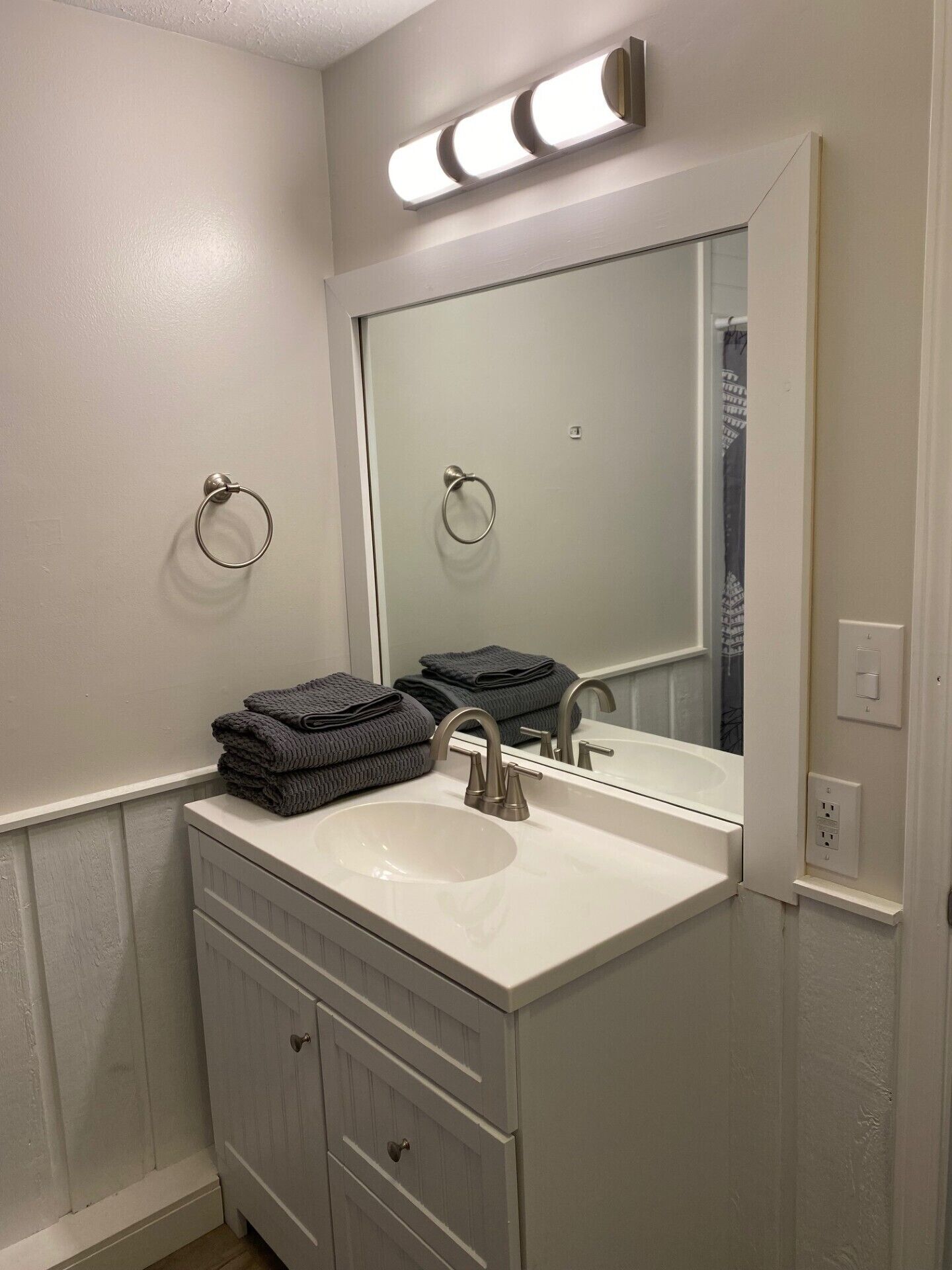 Un bagno con un mobile lavabo bianco, un lavandino, uno specchio e un portasciugamani.
