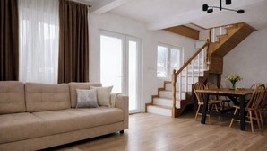 Un salon spacieux avec un canapé beige, une table à manger en bois et un escalier doté de rampes en bois.