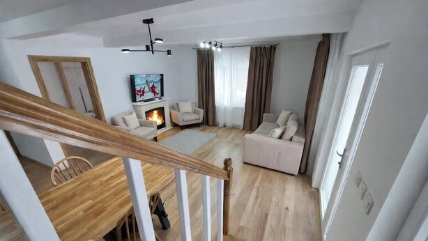 Amplia sala de estar con chimenea, asientos y una escalera.