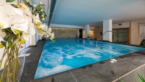 An indoor swimming pool with clear blue water, surrounded by dark stone tiles and a modern interior design. - Zenit Hotel (Giulianova)