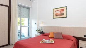 A hotel room with a bed, a tray of breakfast items, a window with blinds, and a wall-mounted picture. - Zenit Hotel (Giulianova)