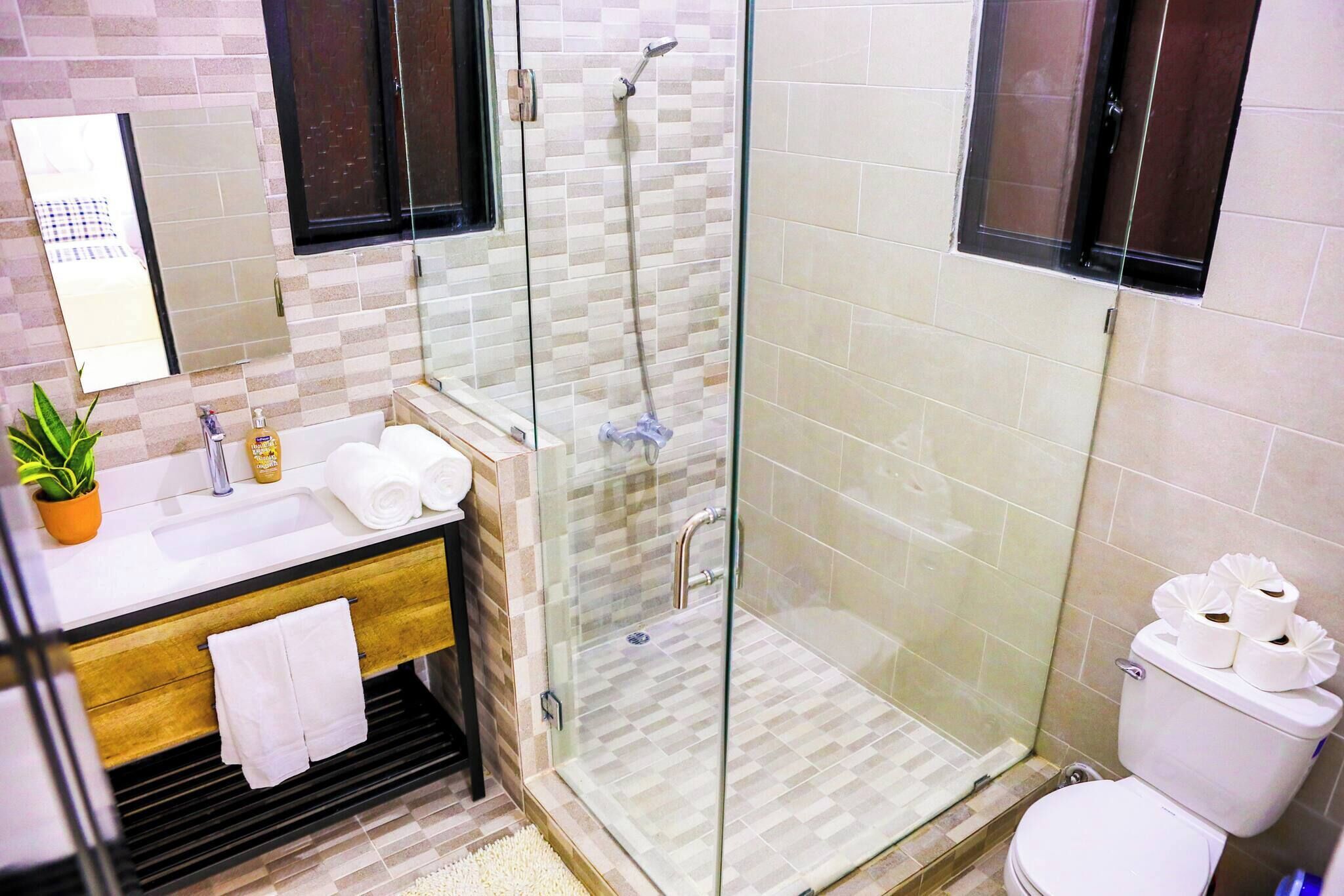 A modern bathroom with a glass-enclosed shower, a sink with a mirror, and a toilet.