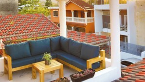 A covered outdoor seating area with a sofa, coffee table, and planters. - Agapimou Apartments H (Gaspar Hernandez)