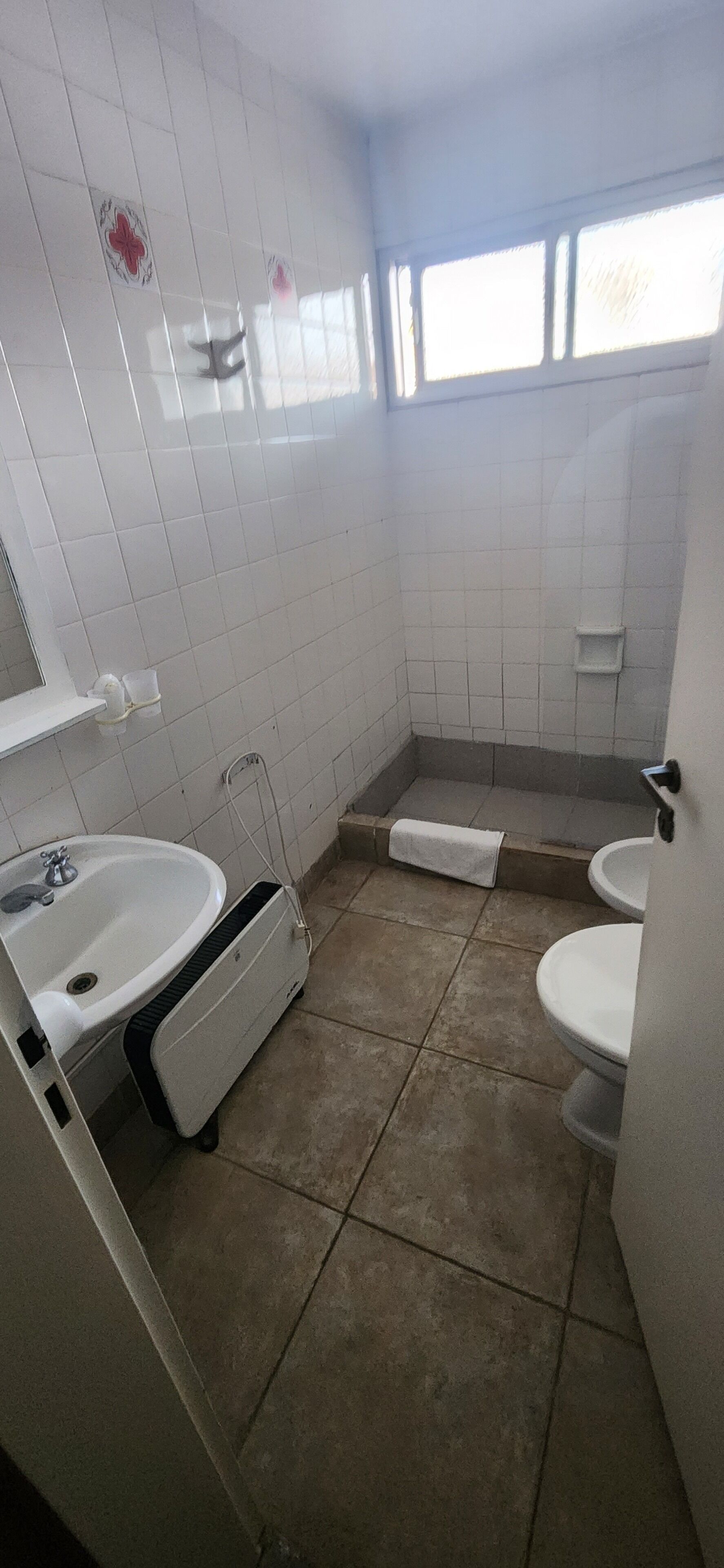 A small bathroom with a sink, toilet, and shower area.