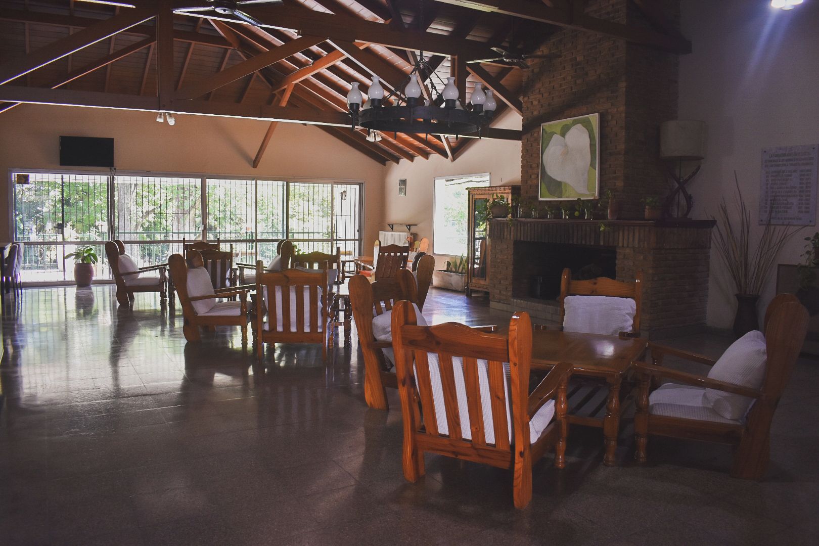 A spacious room with wooden furniture, large windows, and a fireplace.