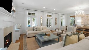 Un salon avec une cheminée, un canapé, une table basse et un coin repas avec des chaises.