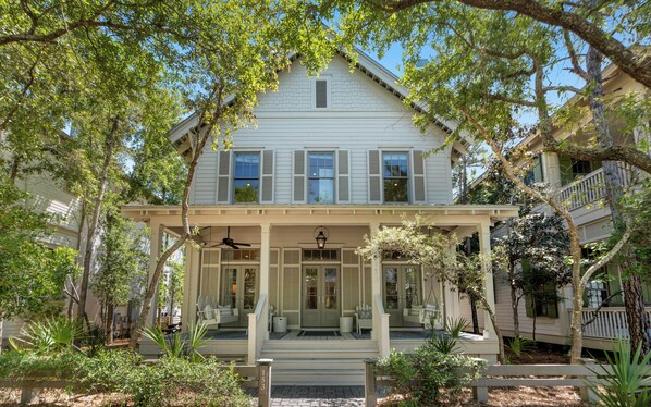 A two-story house with a covered porch, a front door, and a staircase leading to the entrance. - Pelican & Palm - WaterColor Home & Golf Cart! (Santa Rosa Beach)