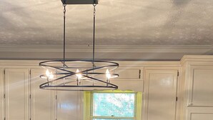 A modern kitchen with white cabinets, a stainless steel dishwasher, a black trash can, and a unique spiral light fixture. - Spacious 4-bedroom house in charming Lawrenceville with AC (Lawrenceville)