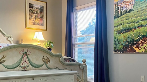 A bedroom with a bed, a painting, a window with curtains, and a lamp. - Spacious 4-bedroom house in charming Lawrenceville with AC (Lawrenceville)