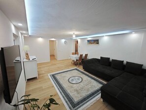 A modern living room with a black sofa, a white coffee table, and a patterned rug. - Charming Family Apartment in Wutöschingen With Garden View (Wutoeschingen)