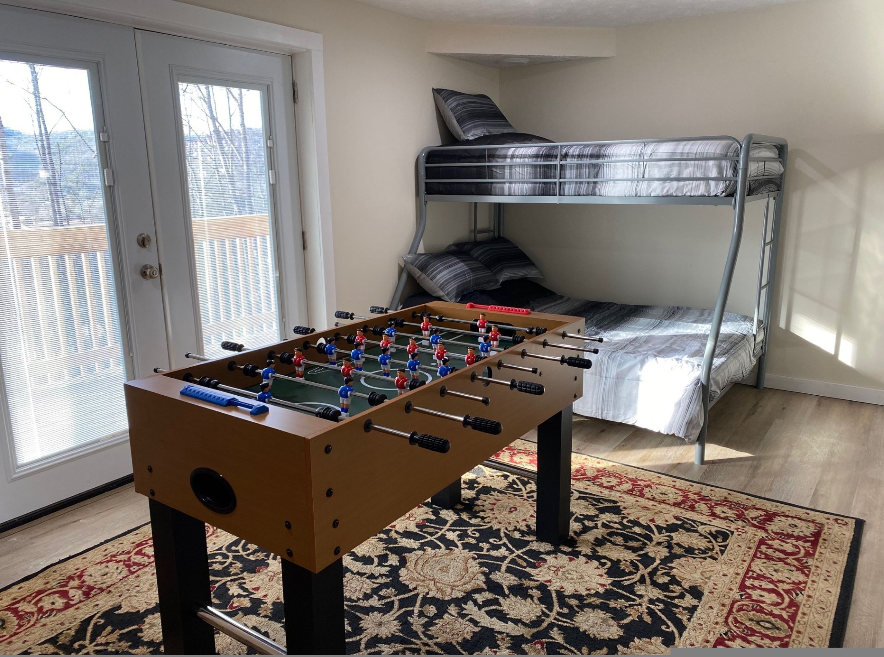 Una habitación con mesa de fútbol, literas y una alfombra estampada.