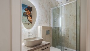 Ein modernes Badezimmer mit einem großen, ovalen Waschbecken, einer Duschkabine aus Glas und einer Toilette.