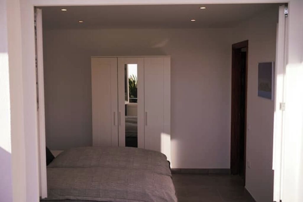 Un dormitorio con cama, armario y puerta que da a otra habitación.