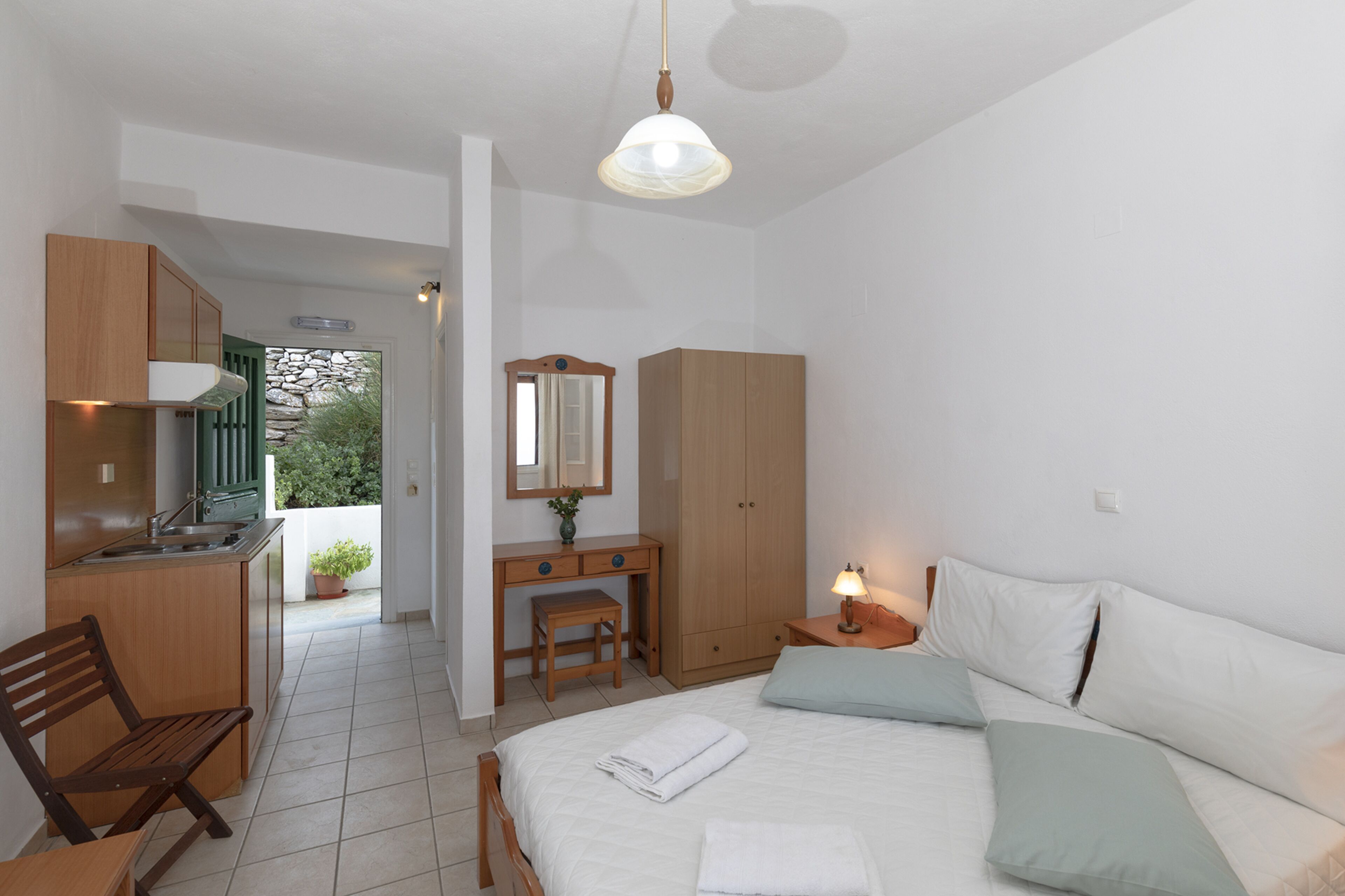 Un dormitorio con cama, mesita de noche, lámpara y vistas a una zona de cocina.