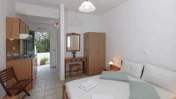 Un dormitorio con cama, mesita de noche, lámpara y vistas a una zona de cocina.