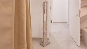 A hallway with a beige curtain, a tall, narrow column, and a white door leading to another room. - Suites Gaudioso Napoli Center (Naples)