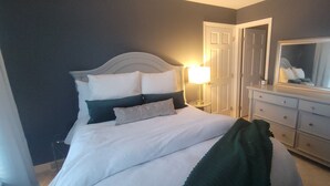 Una camera da letto con un letto, una cassettiera, uno specchio e un comodino.