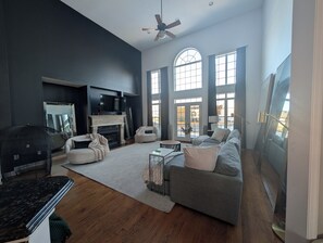 A spacious living room with a fireplace, large windows, and a ceiling fan. - Spacious 4-bedroom family friendly house, convenient to airport and downtown (Clinton)