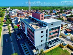 A modern multi-story building with a flat roof, large windows, and a parking area. - Studio piscina privativa 10 by La Playa (Ipojuca)