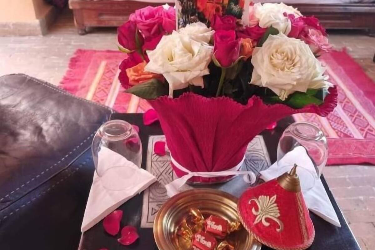 Una habitación ordenada con una cama, una mesa con un florero, un plato decorativo y un cuenco pequeño.