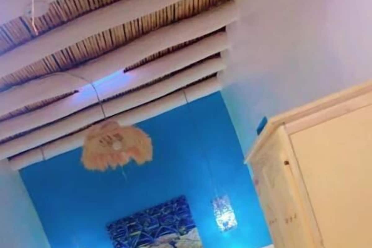 Un dormitorio con una pared azul de acento, una colcha amarilla y un cabecero blanco.