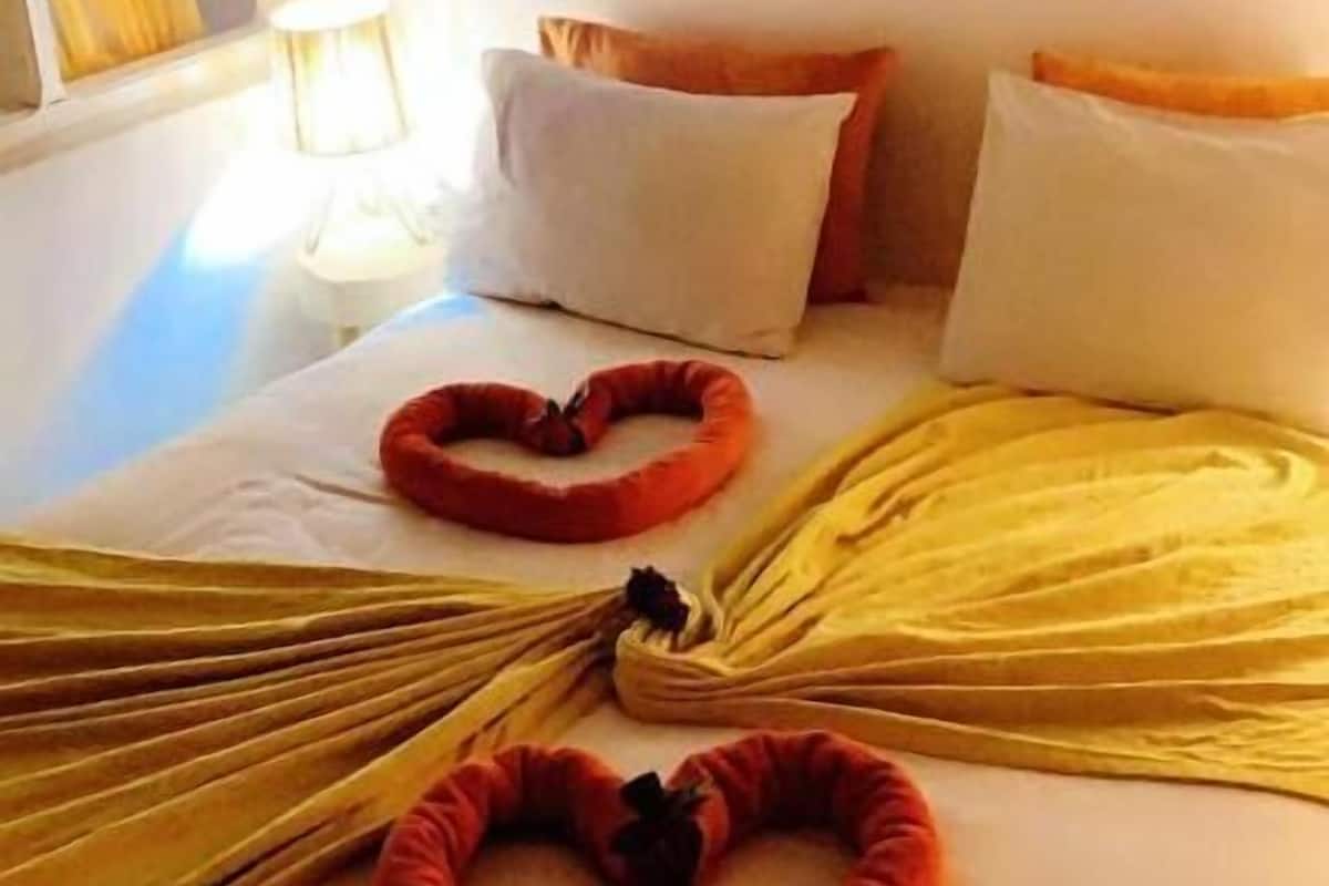 Una cama con almohadones con forma de corazón y un adorno con forma de sol en la pared.