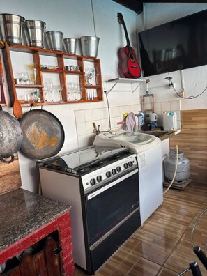 A compact kitchen with a stove, sink, and various utensils. - Pousada Recanto Alto Da Boa Vista (Cachoeira Paulista)