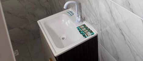 Un baño con un lavamanos blanco, un espejo y baldosas de mármol.