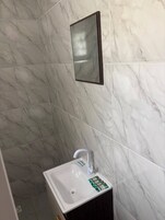 Un baño con un lavamanos blanco, un espejo y baldosas de mármol.