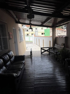 An outdoor patio with a black leather sofa, a wooden table, and a bench.