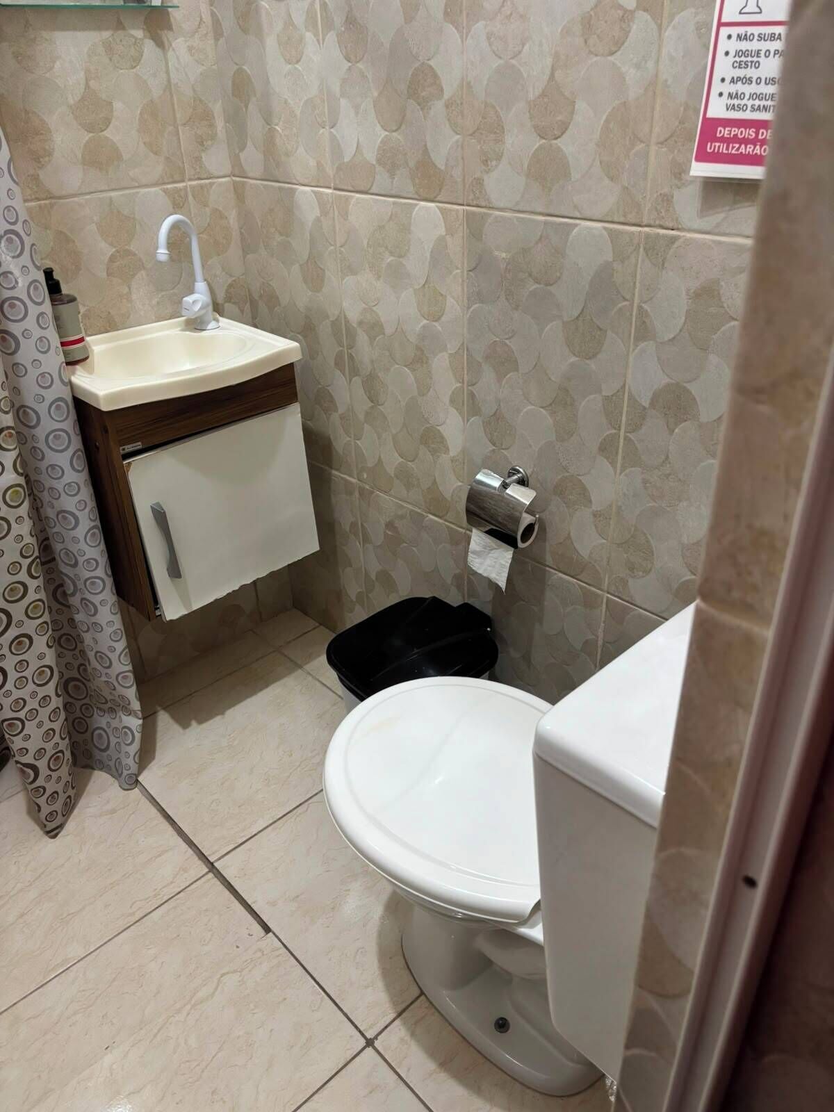 Un baño pequeño con inodoro, lavamanos y un cubo de basura.