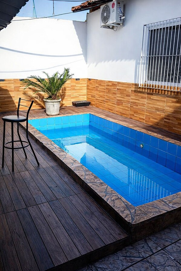 Une piscine avec une terrasse en bois et une chaise.