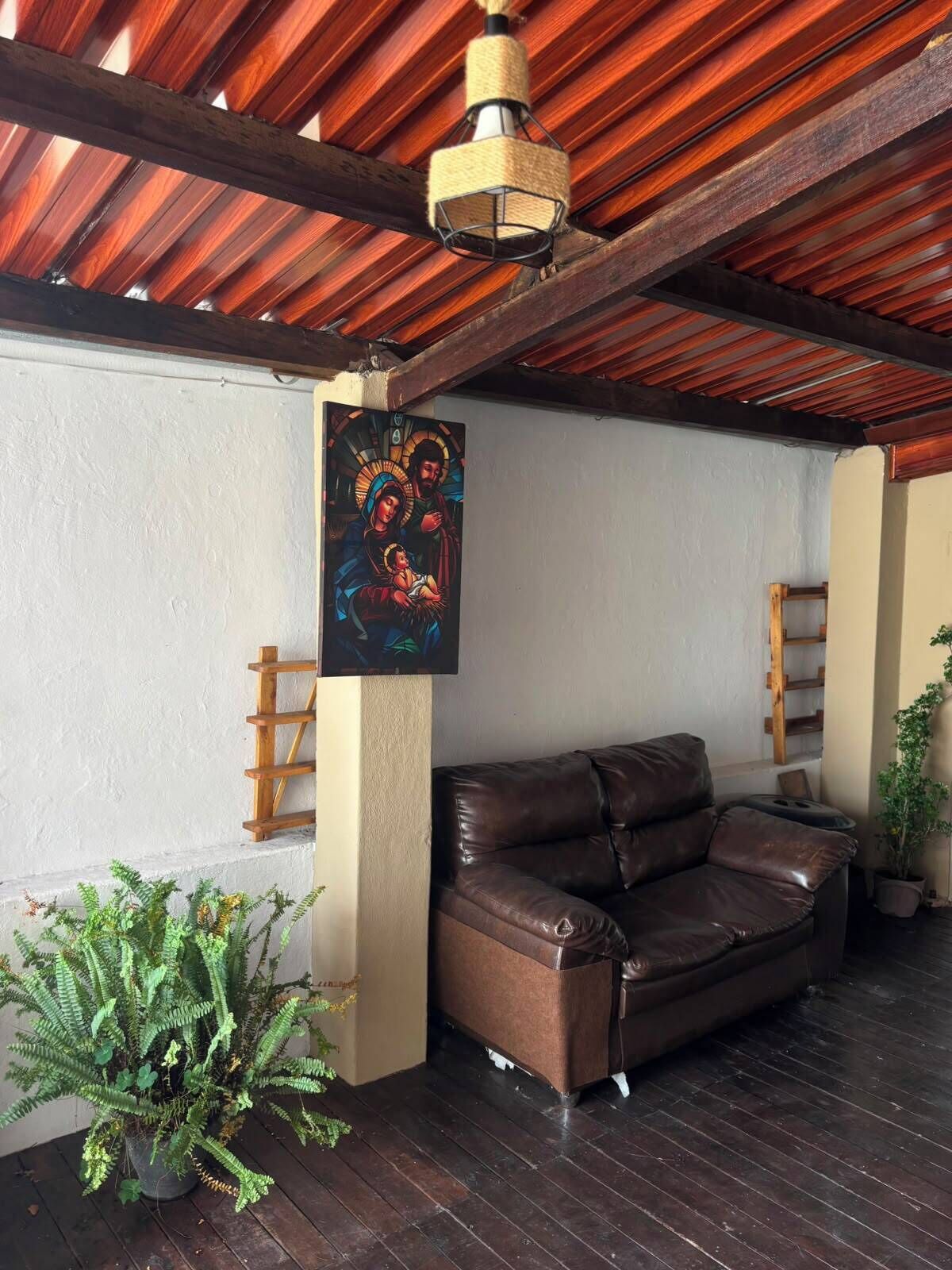 Una habitación con techo de madera, un sofá de cuero marrón, un cuadro en la pared y una planta en maceta.