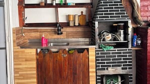 A kitchen with a brick oven, wooden shelves, and a wooden counter. - Pousada Recanto Alto Da Boa Vista (Cachoeira Paulista)