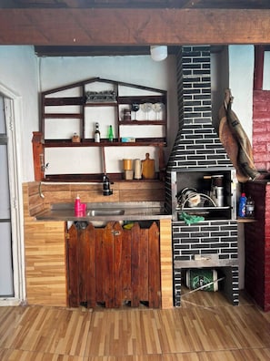 A kitchen with a brick oven, wooden shelves, and a wooden counter.
