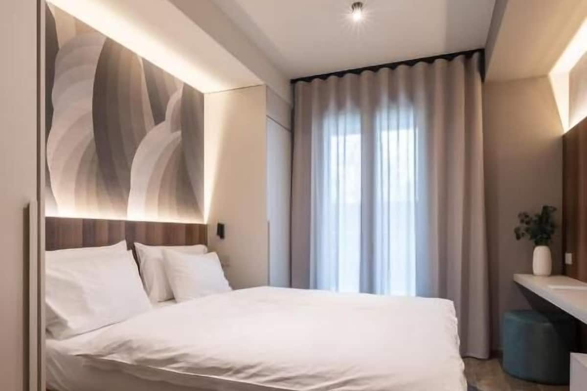 A modern bedroom with a large bed, a built-in headboard, and a bedside table.