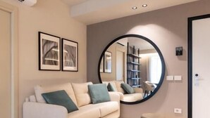 A modern living room with a beige sofa, a round mirror, and a blue ottoman. - Stemor srl (Desenzano del Garda)