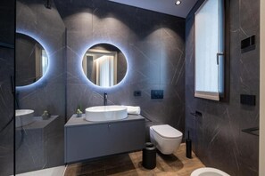 Un baño moderno con un espejo redondo, un lavabo blanco y un inodoro.