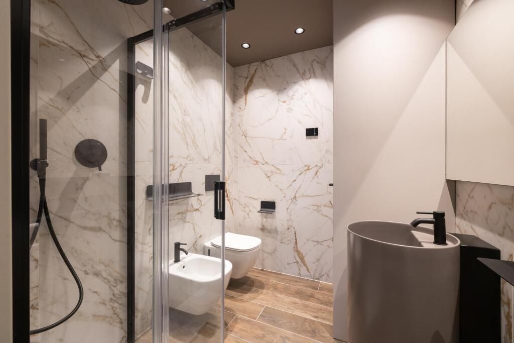 Une salle de bain moderne avec une douche à parois de verre, un bidet et un grand lavabo.